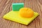 Cleaning sponge, brush scrubber and yellow micro fiber cloth on wooden background. Household