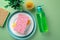 Cleaning sponge on plate with dishwashing liquid soap and natural brush on green background