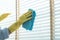 The cleaning staff uses a cloth and dust brush on the window surface with blinds and uses cleaning agents to kill germs and