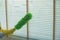 The cleaning staff uses a cloth and dust brush on the window surface with blinds and uses cleaning agents to kill germs and