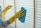 The cleaning staff uses a cloth and dust brush on the window surface with blinds and uses cleaning agents to kill germs and