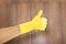 Cleaning success. Thumbs up of hand in yellow protective glove