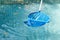 Cleaning swimming pool of fallen leaves with blue skimmer net