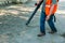 Cleaning up falling leaves in city park during spring sunny dry time. Using a blower for cleaning in the park. The concept of