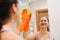 Cleanness in every move. Pretty brunette cleans mirror with help of yellow cloth and special mean of cleaning