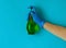 Cleanser is held by female hand in blue glove on blue background.The cleanser is green
