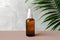 Clear amber glass spray bottle mockup with tropical green leaf. Natural organic cosmetic or herbal medicine product. Minimal style