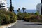 Clear blue sky,azure sea,waves,many green trees and flowering shrubs,palm trees,hotels for vacationers,road leading to the beach