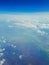 Clear blue sky and white clouds from airplane window. Vertical photo, travel concept