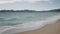 Clear blue waves with strong wind on a sandy empty beach in Cannes with Theoule-sur-Mer on background