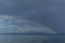 clear calm undulating blue water of Lake Baikal, mountains on the horizon, colorful rainbow in sky