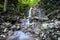 Clear and fresh mountain spring water flows and splashes over a stone down a waterfall - long time water exposurephoto
