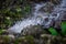 Clear and fresh mountain spring water flows and splashes over a stone - Macro photo of the cold and clear water drop