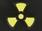 Clear glass black and yellow nuclear symbol isolated on a dark g