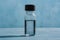 Clear glass vial with dark cap, light blue background, textured liquid surface