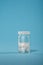 Clear Glossy Plastic Bottle with White Cap and white capsules on blue background