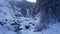 A clear mountain river runs through a snowy gorge