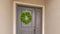 Clear Panorama Gray front door of a home with a simple green wreath and sidelight