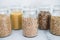 Clear pantry jars with different types of grains in them including quinoa rice buckwheat couscous and barley, simple na