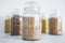 Clear pantry jars with different types of grains in them including quinoa rice buckwheat couscous and barley, simple na