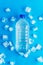 Clear plastic bottle with cold clean drinking water and ice cubes on blue background