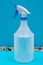 Clear Plastic Spray Bottle made with up to 10% recycled material with blue handle isolated on blue