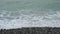 Clear sea waves over pebbles beach.