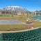 Clear Square Baseball field with green tiered seating against mountain and vibrant blue sky