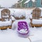 Clear Square Purple sled in the middle of wooden chairs on a frosted ground in winter