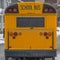 Clear Square Rear of a yellow school bus against snowy homes and cloudy sky in winter