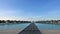 A clear sunny day in the Maldives. A wooden platform goes from the sandy shore to the villas on the water.