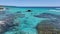 Clear turquoise waters with a rocks, a moving boat, and scattered seagulls WA