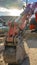 Clear Vertical Close up of a red excavator with an attched grader blade viewed on a sunny day