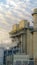 Clear Vertical Power Plant releasing steam against pale blue sky with bright puffy clouds