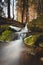 Clear water photographed with long exposure time through flowing rocks covered with moss with autumn colours of leaves. Beskydy