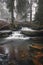 Clear water photographed with long exposure time through flowing rocks covered with moss with autumn colours of leaves. Krasna,