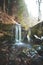 Clear water photographed with long exposure time through flowing rocks covered with moss with autumn colours of leaves and snow