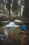 Clear water photographed with long exposure time through flowing rocks covered with moss with autumn colours of leaves and tourist