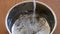 Clear water pouring into metal pot with tiny quail eggs ready to cook boiling