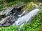 a clear waterfall with big rocks below