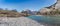 Clear wide mountain river with snow-capped peaks behind under a clear blue sky