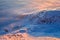 On a clear winter day, from a snow valley powdered with snow, can be seen picturesque snow covered mountain hills.