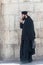 The clergyman stands and talks on his mobile phone in the old city of Jerusalem, Israel.