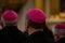 Clerics in the amaranth zucchetto praying during the mass in the chapel