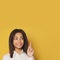 Clever African American student girl pointing up on yellow background