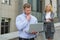 Clever businessman with laptop ahead of business lady who talking to him outdoor