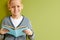 clever cheerful diligent little school boy reading a book over green background, isolated