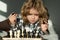 Clever concentrated and thinking child playing chess. Chess game with children at home.