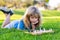 Clever concentrated and thinking child while playing chess, laying on grass in summer park. Chess, success and winning.