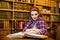 Clever female student girl sitting in library with books.